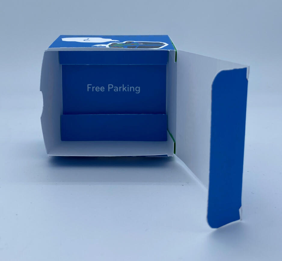 Showing the inside of the Hot Wheels box and how I made a holder to keep the cars more stable, and it says free parking.